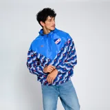 Campera deportiva Umbro Windbreaker del Club Nacional de Football. Diseño con paneles en azul y estampado geométrico en azul, rojo y blanco. Incluye capucha, cierre frontal y logo de Umbro y escudo del club en el pecho.