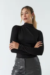 Body negro de poliéster y spandex, con cuello alto tipo polera, mangas largas y frunces laterales.