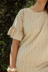 Pijama de algodón con estampado vichy, compuesto por una blusa de manga corta con volados y un pantalón capri con elástico en la cintura y volados en el ruedo.