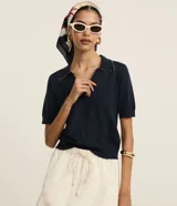 Blusa de punto azul marino con cuello polo, escote en V y mangas cortas. Detalle de mini perlas aplicadas en el cuello.