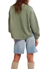 Camiseta de manga larga color verde oliva, con textura acanalada y silueta holgada extragrande. Presenta escote redondo, hombros caídos y puños anchos.