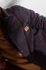 Camisa de franela escocesa con cuello, cierre frontal con botones, dos bolsillos con solapa abotonada en el pecho y corte recto.