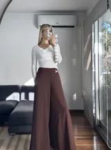 Blusa blanca de poliéster labrado, con cuello drapeado estilo bote y mangas largas.