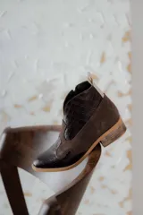 Botines de cuero marrón y blanco con diseño western, puntera redondeada y cierre lateral con cremallera. El talón tiene una tira de cuero para facilitar el calce.