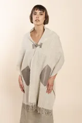 Chal de lana fina sin teñir, con calce en hombros, abrochadura con alamar de fieltro, bolsillos de cuero y terminación con flecos. Diseño exclusivo de Don Baez, hecho en Uruguay.