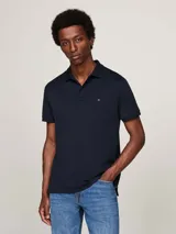 Chomba Tommy Hilfiger de corte regular, color azul marino, confeccionada en algodón. Presenta cuello tipo polo, cartera de dos botones y logo bordado en el pecho.