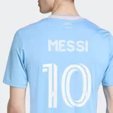 Camiseta de fútbol Adidas del Inter Miami CF, modelo 25/26. Diseño celeste con rayas sutiles y detalles en rosa. Incluye escudo del club, logo de Adidas y nombre y número de Lionel Messi.