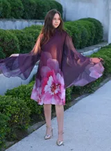 Vestido corto con cuello alto y mangas anchas, color morado con estampado floral en tonos rosados y blancos.