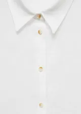 Camisa blanca de lino con cuello clásico, manga corta y cierre frontal con botones.