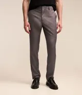 Pantalón de vestir gris, de corte slim fit, con bolsillos laterales y traseros. Se ajusta a la cintura con cinturón de cuero negro.