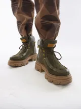 Botas de caña media color marrón de cuero gamuzado, con suela track y cordones rojos.