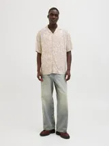 Camisa de manga corta color beige con estampado abstracto blanco, cuello resort, cierre con botones y corte relajado. Confeccionada en viscosa LENZING™ ECOVERO™.