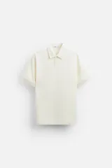Polo color crema de corte recto, con cuello solapa y cierre frontal de botonadura.