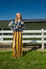 Falda larga tejida a mano con rayas horizontales marrones y amarillas, con flecos en el ruedo.