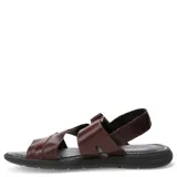 Sandalias de hombre color marrón oscuro, con tiras anchas de cuero texturizado que se cruzan sobre el empeine y una tira ajustable con velcro en el talón. Suela negra gruesa.