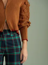 Cardigan marrón de tejido de punto con cierre frontal, cuello redondo y mangas abullonadas con apliques de pompones.