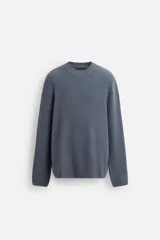 Sweater azul de punto con textura, corte holgado, cuello redondo y mangas largas con puños acanalados.