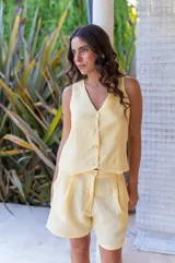 Conjunto de dos piezas color rojo vibrante, compuesto por un chaleco sin mangas con escote en V y botones frontales, y un short de tiro alto con pliegues y bolsillos laterales.