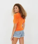 Blusa color naranja con textura de peluche, manga corta y cuello redondo.