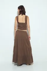 Falda larga maxi de algodón color marrón, con textura acanalada sutil. Presenta cintura elástica con cordón de ajuste y estructura en paños que añaden volumen y caída fluida.