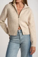 Cardigan de punto color beige melange con textura tweed, cuello alto y cierre frontal metálico. Corte ajustado al cuerpo y manga larga.