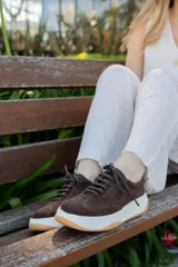 Zapatillas acordonadas de cuero color marrón, con suela blanca y base color caramelo.