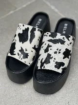 Sandalias tipo sueco con plataforma de goma negra y tira ancha de cuero con estampado animal print de vaca.