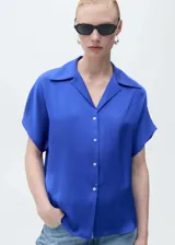 Camisa azul eléctrico de manga corta con tejido satinado, corte regular, cuello camisero y cierre frontal con botones.