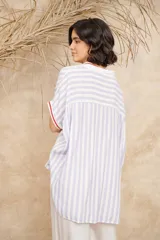 Camisa amplia de manga corta con rayas verticales celestes y blancas, con cuello clásico y terminaciones en rojo.