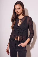 Blusa negra traslúcida de viscosa con textura arrugada, mangas largas acampanadas y escote en V con lazos.