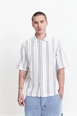 Camisa de manga corta con corte oversize, a rayas verticales blancas y grises, con cuello clásico y cierre frontal con botones. Confeccionada en algodón.