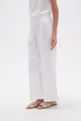 Pantalón blanco de algodón con calce recto y tiro bajo. La tela presenta bordados tipo calado (broderie) a lo largo de toda la prenda.