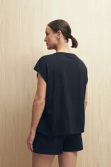 Remera negra de manga corta con estampado floral y tipográfico en tonos marrones.