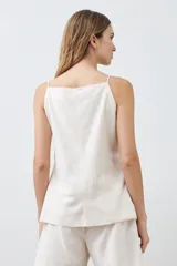 Chaleco color beige con botones de nácar, sin mangas y con bolsillos frontales.