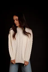 Sweater tejido de punto color rosa pastel, con cuello alto y diseño de trenzas verticales.