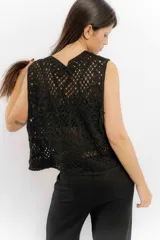 Chaleco blanco de encaje con diseño floral, corte sastrero y sin mangas.