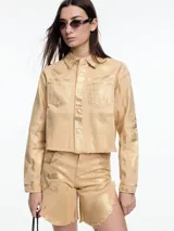 Campera corta de denim color rojo con textura metalizada, cuello camisero, cierre frontal con botones a presión, bolsillos de parche en el pecho y ruedo desflecado.