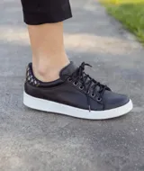 Zapatillas acordonadas de cuero color marrón con detalles dorados en el talón y suela blanca.