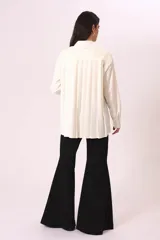 Camisa blanca de corte oversize, con cuello clásico y mangas largas con puños abotonados.