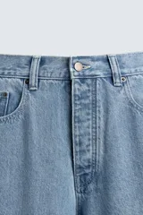 Pantalón de jean celeste de corte holgado y amplio en toda la pierna, tiro medio, tejido rígido, cinco bolsillos, efecto lavado, parche en trasero y bolsillo de vivo en pernera.