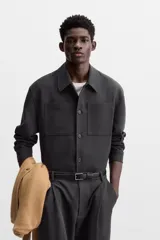 Sobrecamisa verde oscuro de corte cuadrado, con cuello solapa, manga larga con puños abotonados, bolsillos de parche en el pecho y bolsillos laterales en la cadera. Cierre frontal con botones.