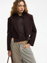 Blazer cropped marrón oscuro con solapa en la parte delantera y camisa desmontable mediante botones. Confeccionado en 97% algodón y 3% elastano.