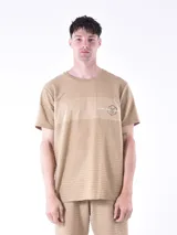Remera color beige con diseño de rayas horizontales y logo estampado en el pecho.