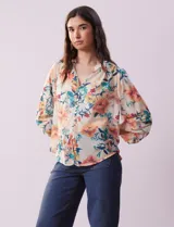 Blusa de gasa estampada con cuello a la base plisado y escote en V. Tiene apertura central con botones de nácar y mangas largas fruncidas. Incluye musculosa interna.