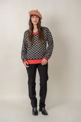 Buzo fino de punto negro con estampado gráfico en tonalidades claras, escote en V y ribetes rojos.
