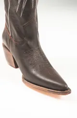 Botas texanas de cuero color marrón con bordados de estrellas y rayos de sol en color blanco. Presentan detalles en rojo en los bordes superiores y un taco de madera. El largo de la caña es de 42cm y la circunferencia de 37cm.