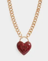 Collar corto con cadena dorada de eslabones gruesos y dije de corazón rojo brillante.