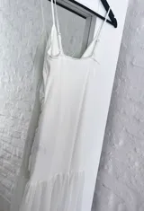 Vestido blanco de breteles finos, con escote en V y falda midi con volados.