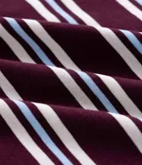 Remera de media malla con cuello polo, manga corta y estampado de rayas horizontales en tonos rosa, blanco y azul.