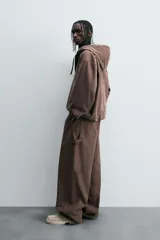 Pantalón negro de corte amplio, confeccionado en tejido de algodón con efecto lavado. Presenta bolsillos frontales, traseros de parche, tira multifunción y bolsillos laterales en las perneras. Cuenta con cierre frontal con cremallera y botón.